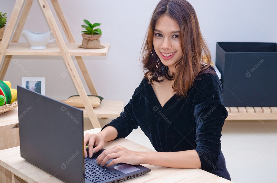 Linda mulher asiática está relaxando usando o notebook do computador na cama.