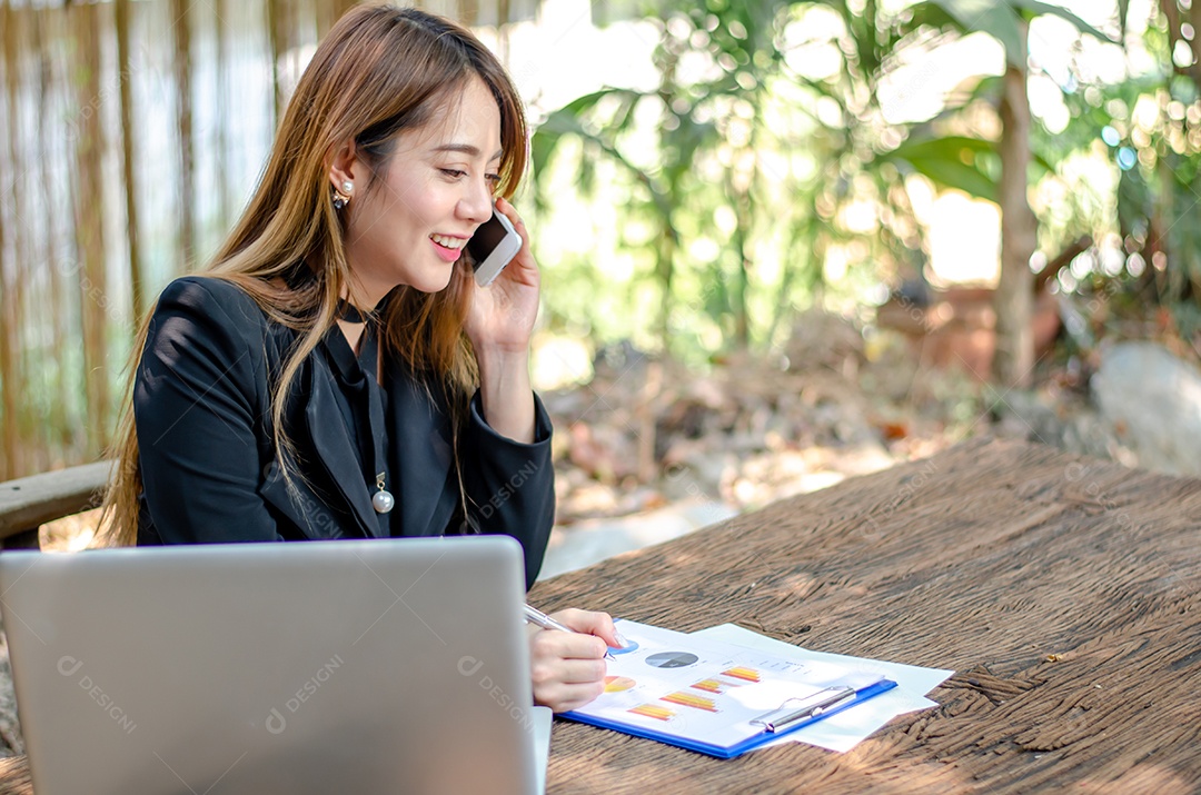Mulher de negócios usa telefones inteligentes, verifica o e-mail e responde à pergunta do cliente na cafeteria ou no espaço de coworking, a garota asiática olha para a mídia social móvel, faz compras on-line, internet banking.