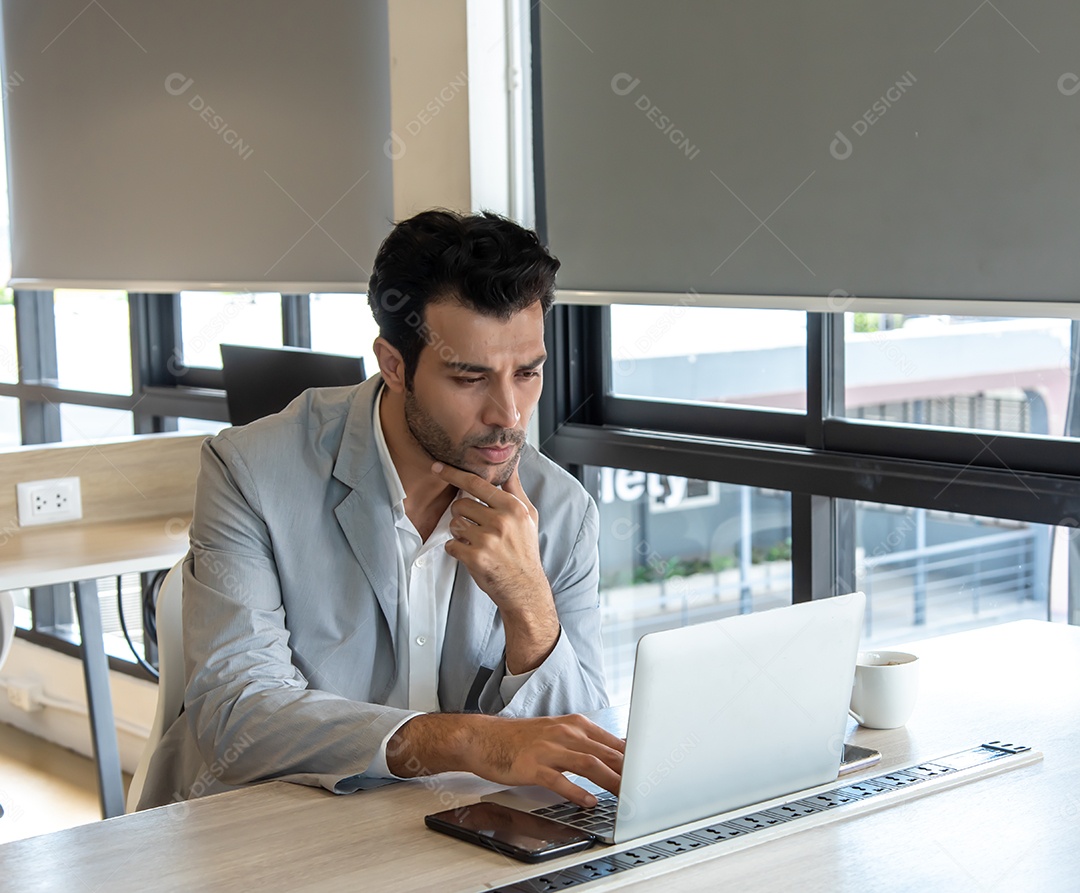 Homem de negócios usa computador portátil no local de trabalho.