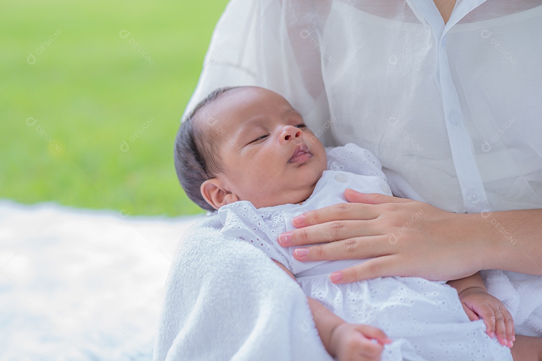 Mãe carrega e toca seu filho com ternura e carinho sentado no parque.