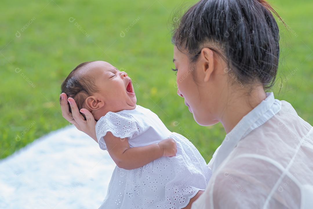 Mãe carrega e toca seu filho com ternura e carinho sentado no parque.