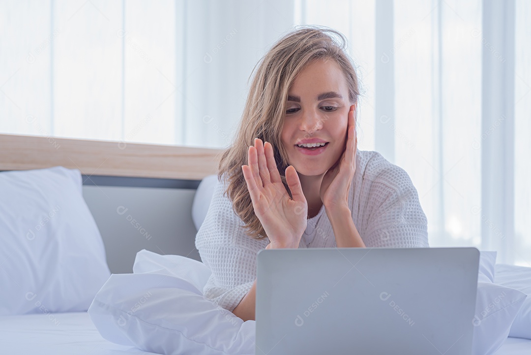 Mulher usando notebook de computador na cama olha rede social na internet.