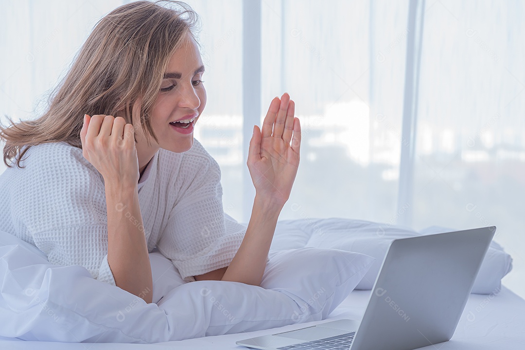 Mulher usando notebook de computador na cama olha rede social na internet.
