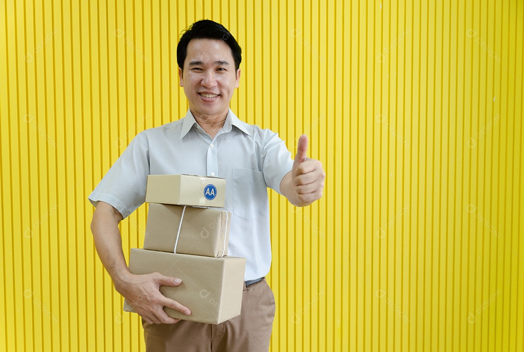 Pequeno empresário asiático feliz segurando dólar e preparando mercadorias para clientes, fundo amarelo.