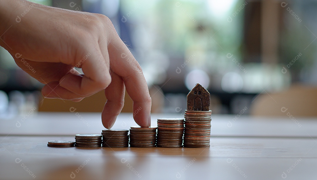 Dedo caminha na pilha de moedas, há um modelo de casa na moeda, investimento em casa.
