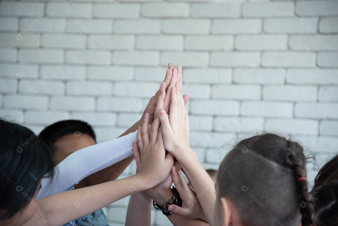 Meninas e meninos da escola primária internacional dão as mãos e trabalham juntos como equipe.