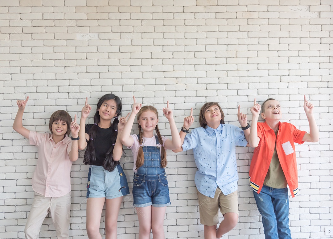 Estudantes masculinos e femininos do ensino fundamental de uma escola internacional ficam na frente da sala de aula.