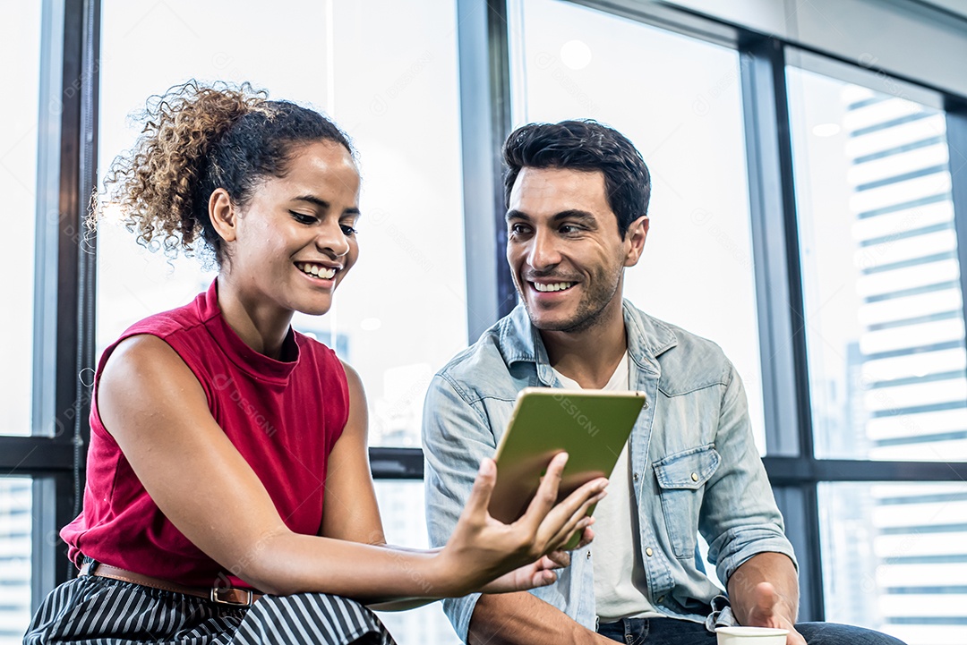 Jovens e mulher e homem assistindo tablet digital no escritório moderno.