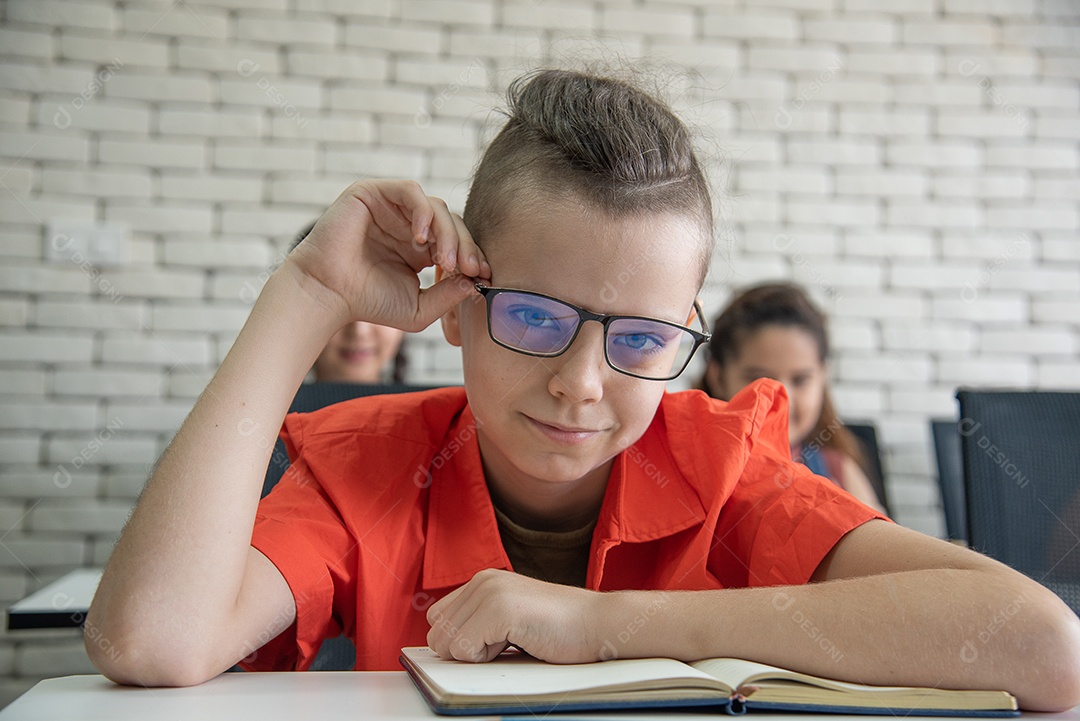 Estudante do ensino médio usando óculos lendo um livro ou fazendo lição de casa na sala de aula.
