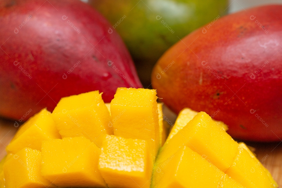 Delicioso pedaço de manga cortado em cubos com frutas ao lado