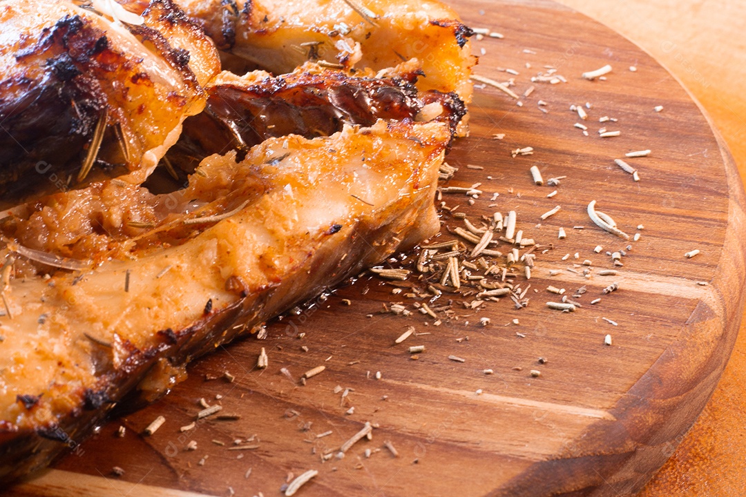 fatias de peixe frito e alecrim na mesa de madeira