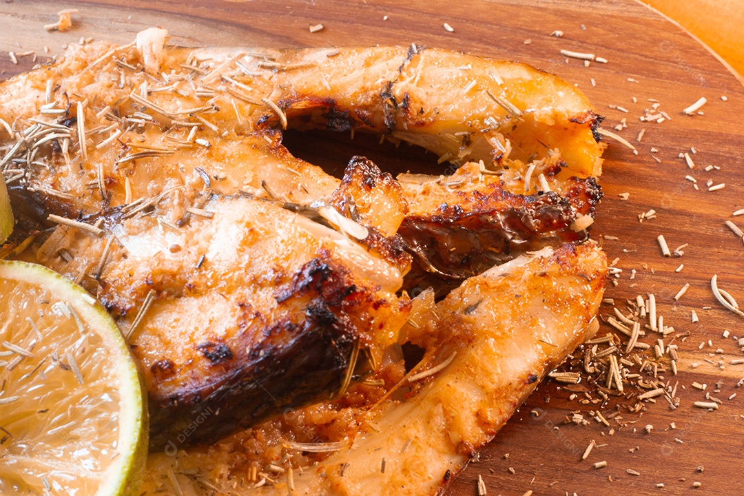 fatias de peixe frito com laranja e alecrim na mesa de madeira