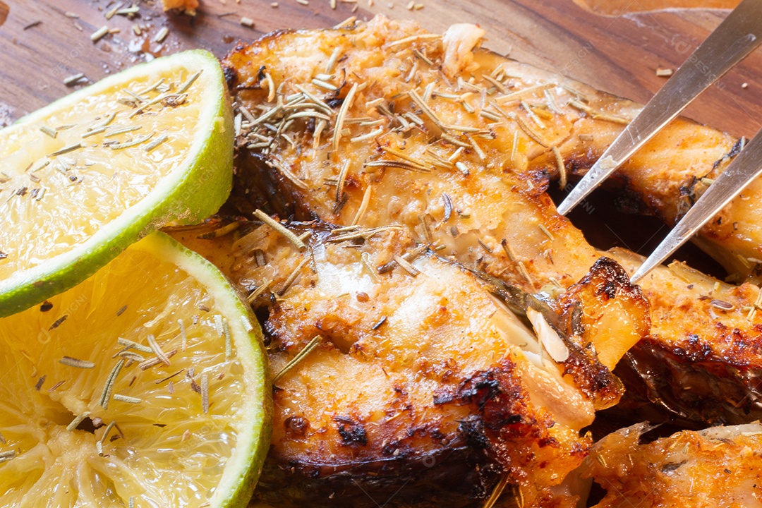 fatias de peixe frito com laranja e alecrim na mesa de madeira