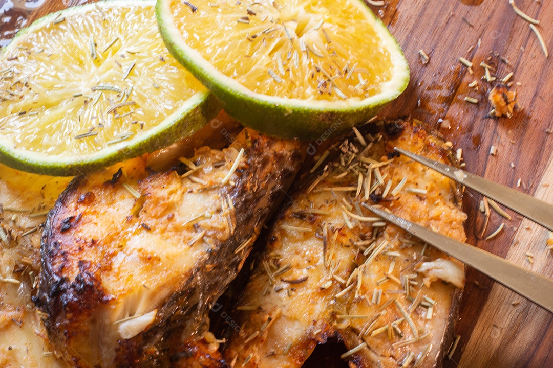 fatias de peixe frito com laranja e alecrim na mesa de madeira