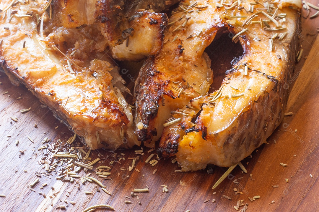 fatias de peixe frito com laranja e alecrim na mesa de madeira