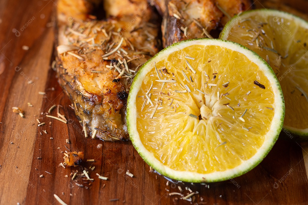 fatias de peixe frito com laranja e alecrim na mesa de madeira