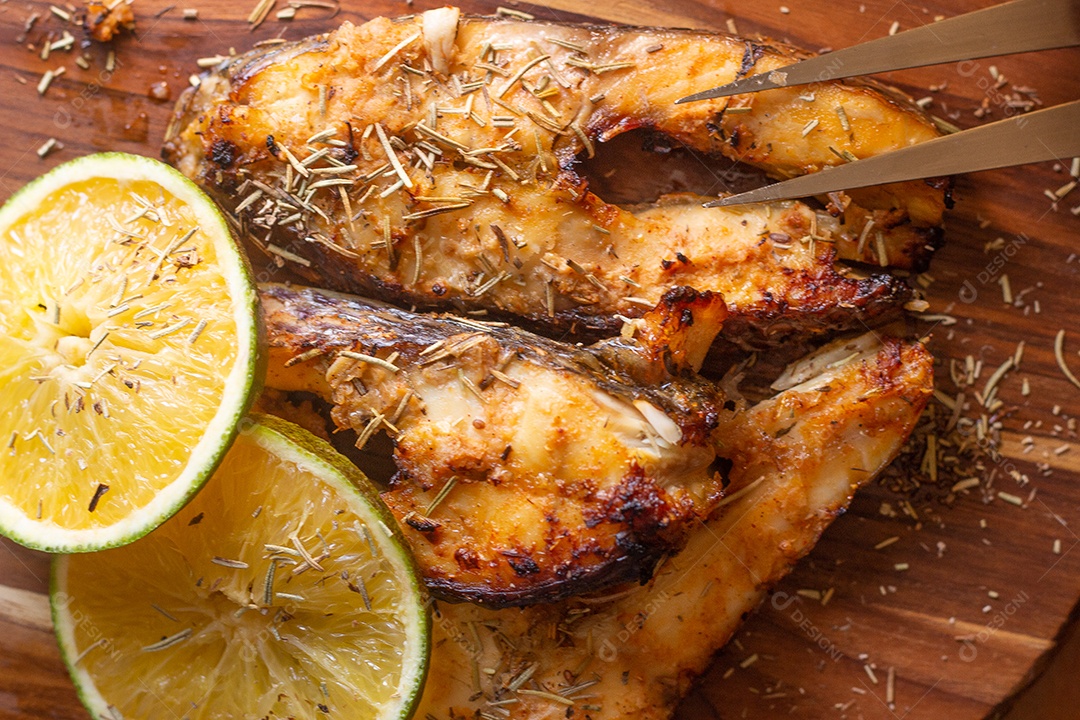 fatias de peixe frito com laranja e alecrim na mesa de madeirac