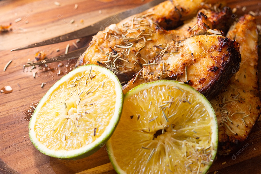 fatias de peixe frito com laranja e alecrim na mesa de madeira