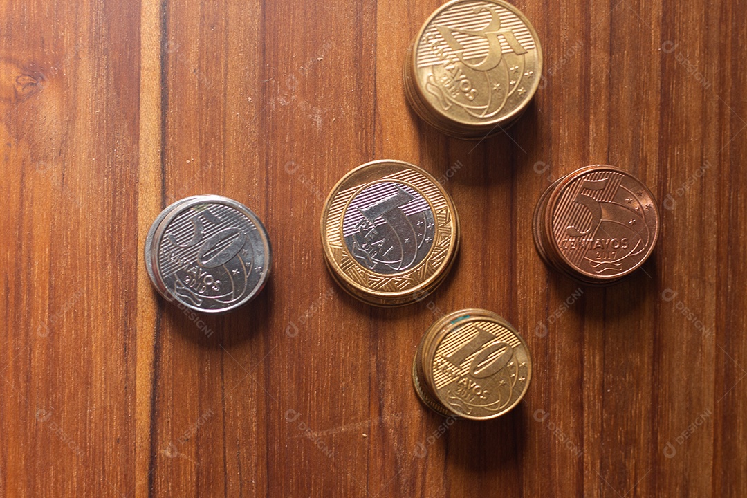 várias cópias da moeda real brasileira debaixo da mesa de madeira