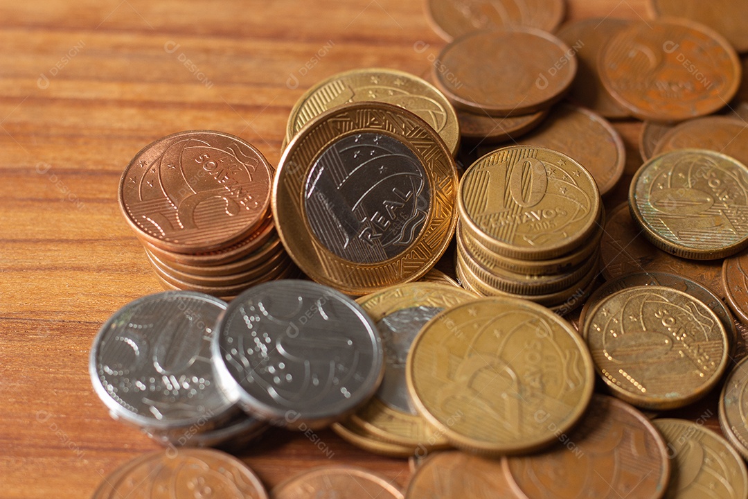 várias cópias da moeda real brasileira debaixo da mesa de madeira