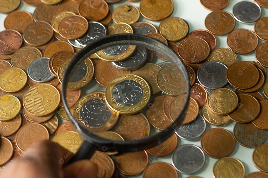 Moeda real brasileira cercada por moedas com fundo preto