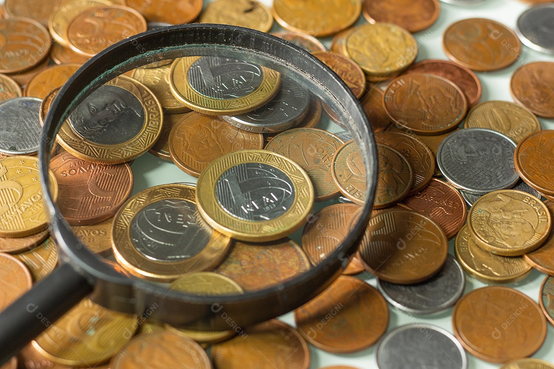 Moeda real brasileira cercada por moedas com fundo preto