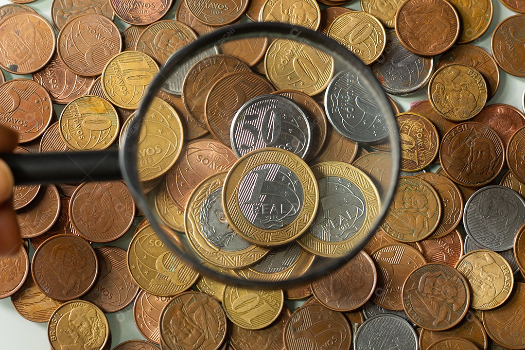 Moeda real brasileira cercada por moedas com fundo preto