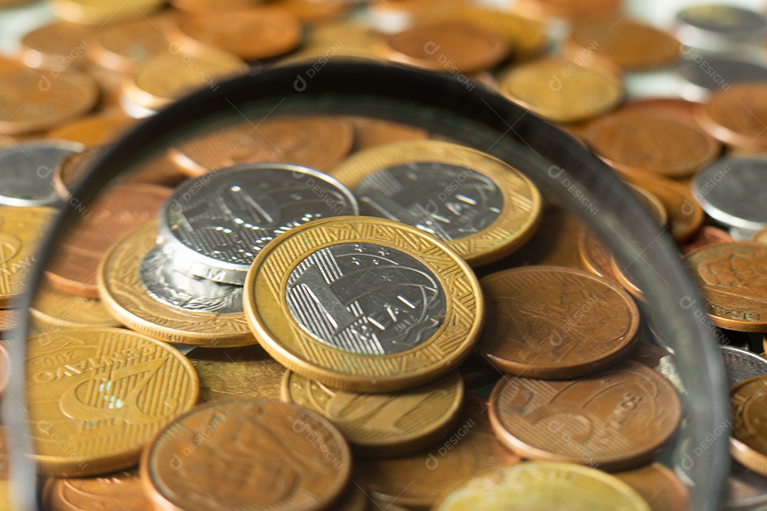 Moeda real brasileira cercada por moedas com fundo preto