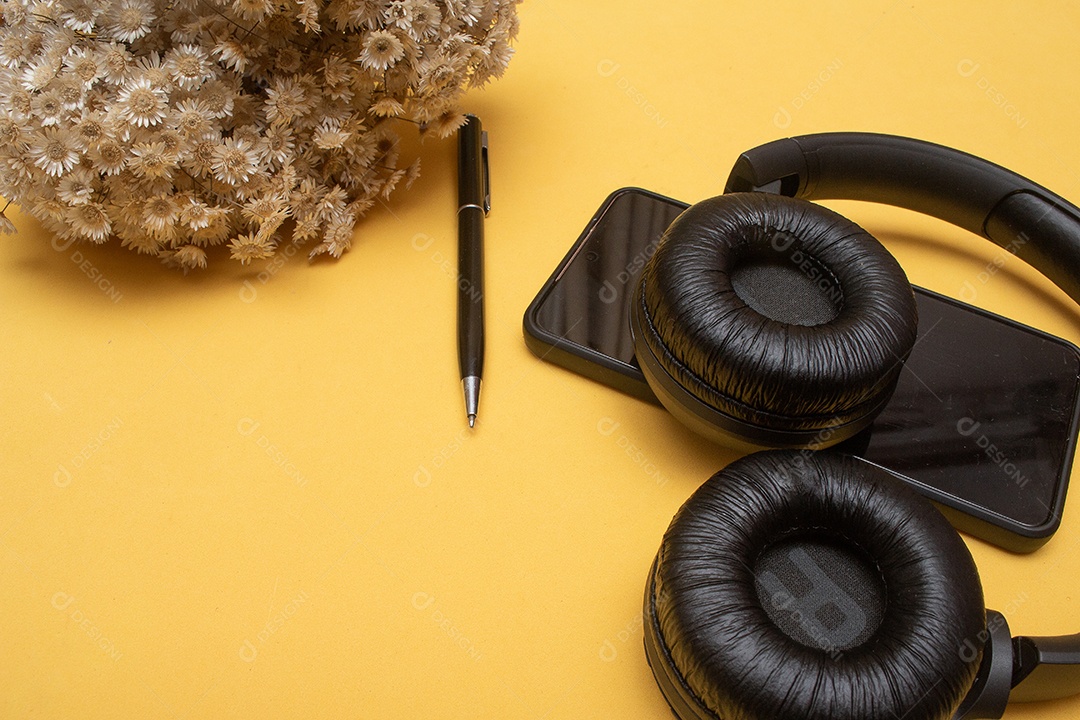 celular e fone de ouvido na mesa em fundo amarelo - escritório