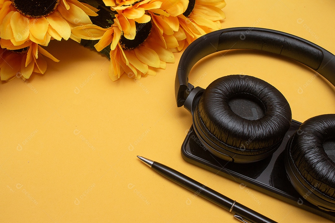 celular e fone de ouvido na mesa em fundo amarelo - escritório
