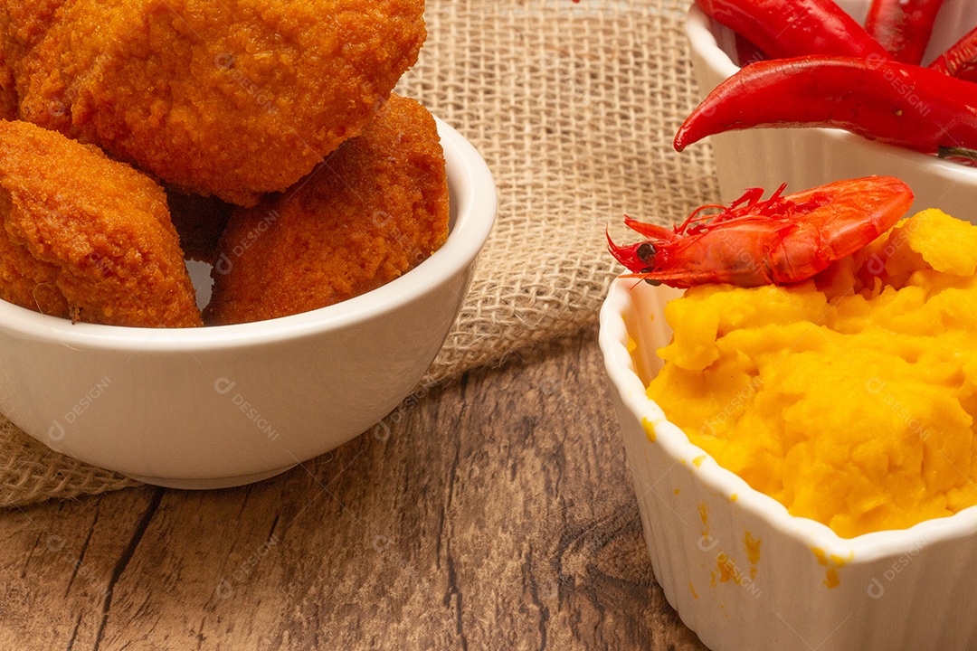 Comida típica da Bahia chamada acarajé cercada de pimenta vermelha