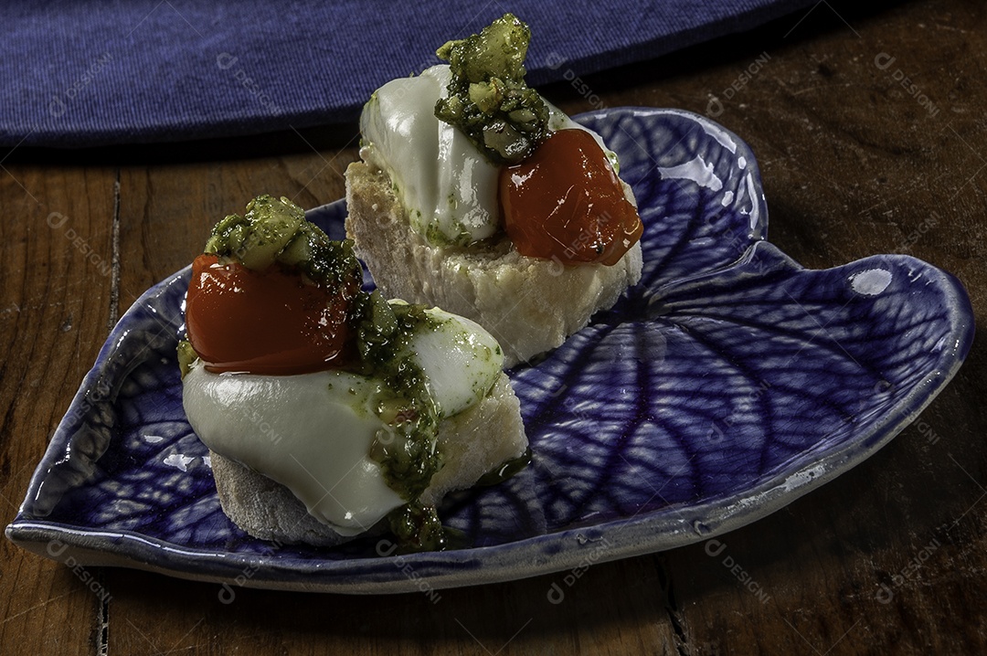 Burrata servida com azeite virgem extra, tomate e manjericão com pães em fatias.