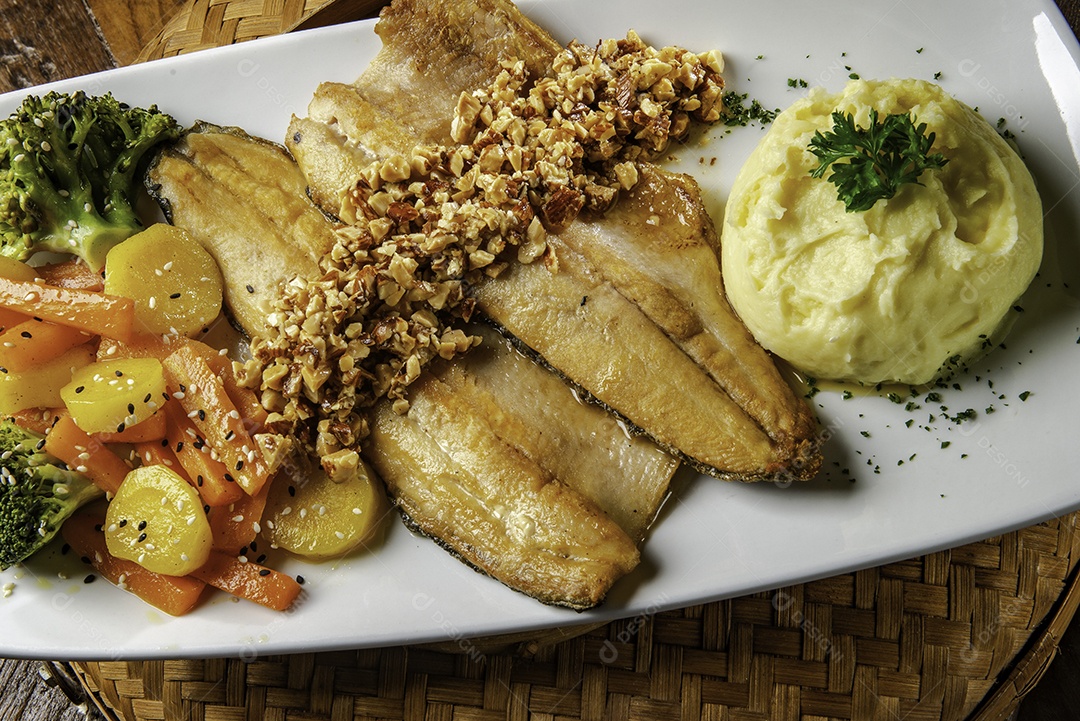 Truta servida com castanhas, pure de batata e legumes.