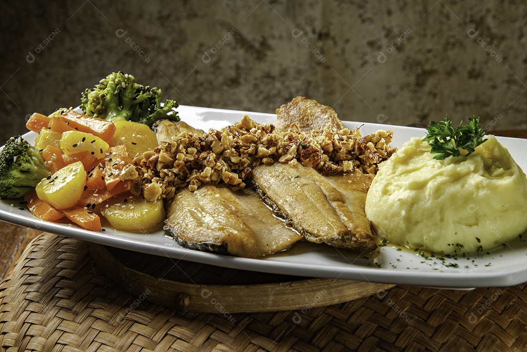 Truta servida com castanhas, puré de batata e leguminosas.