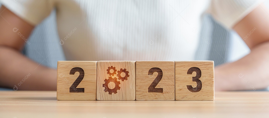 mão de uma mulher segurando o bloco 2023 com o ícone de engrenagem. Processo de negócios, equipe, trabalho em equipe, objetivo, alvo, resolução, estratégia, plano, ação, motivação, mudança, brainstorm e conceitos de início de ano novo