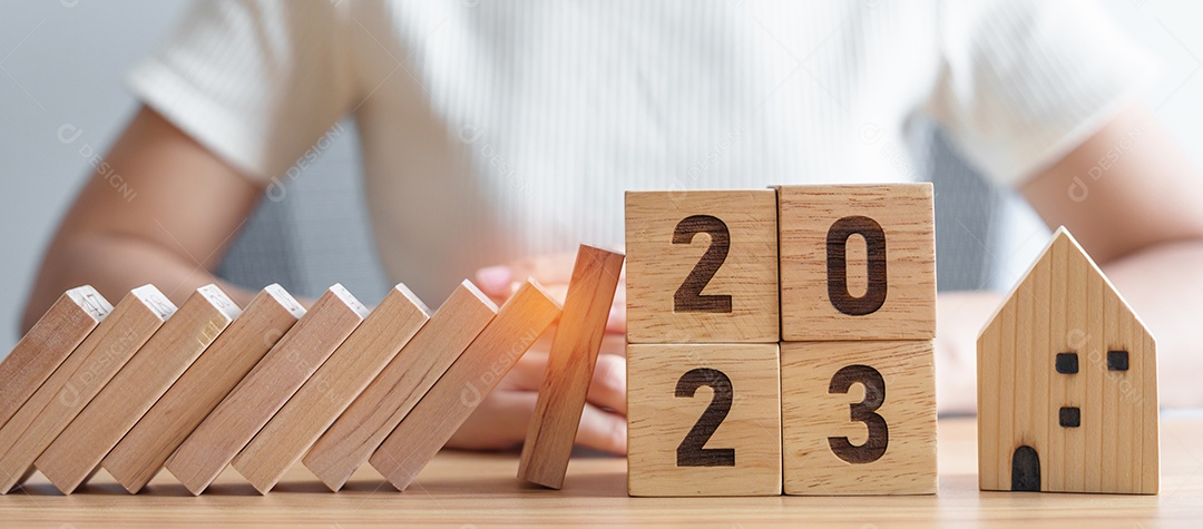 blocos caindo com 2023 anos protegem a miniatura da casa. Inflação financeira, seguro residencial, investimento, crise, recessão econômica, ano novo, conceito imobiliário e de propriedade