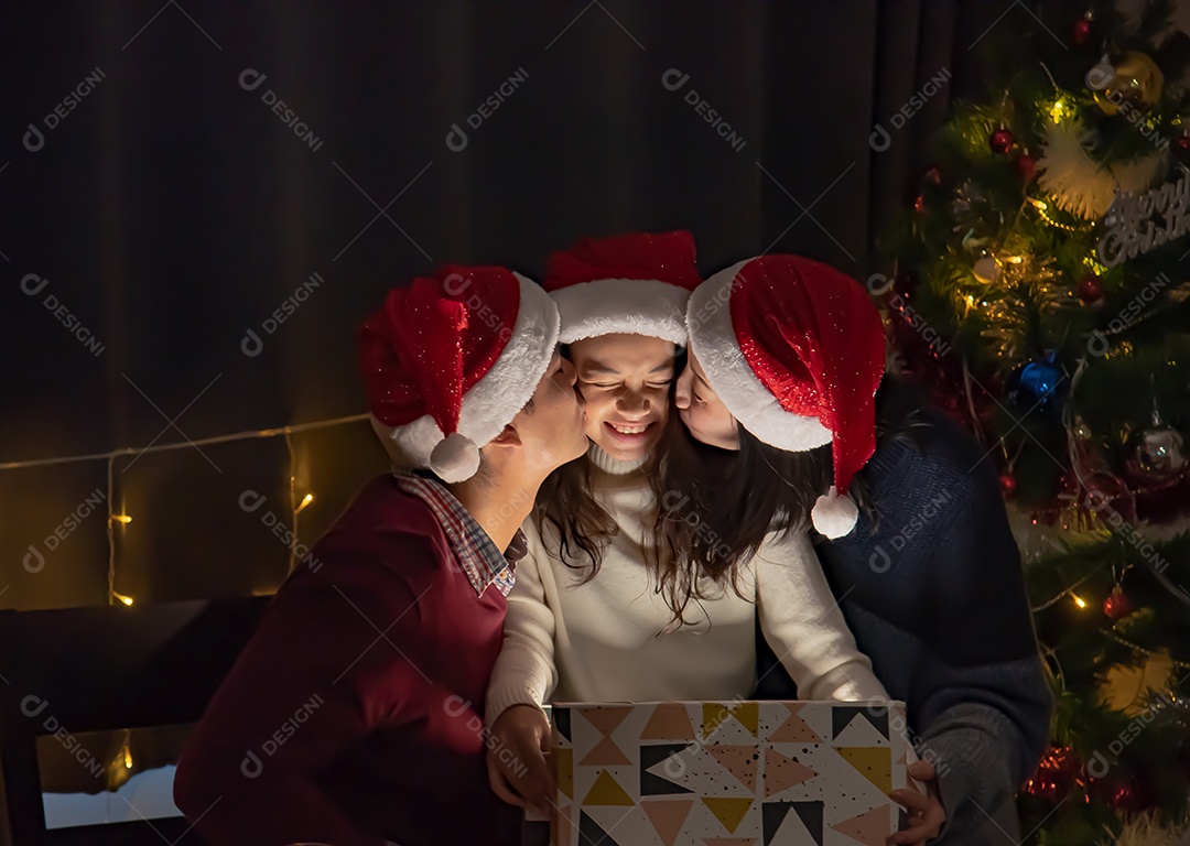 Pais e filhas se beijam ao abrir caixas de presente no dia de Natal.