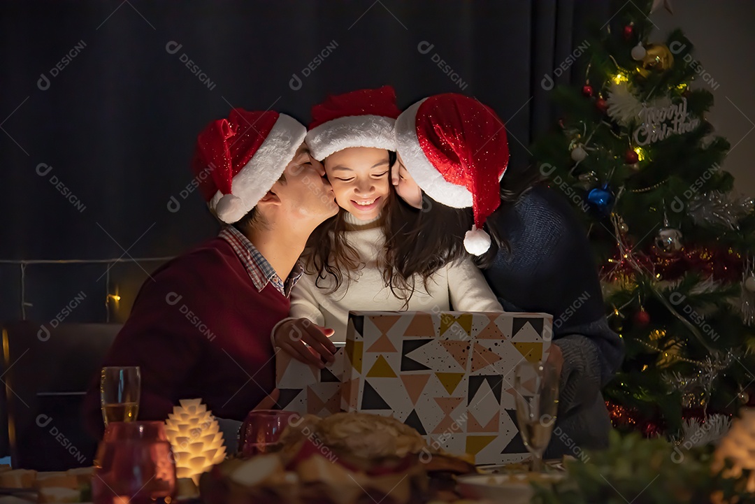 Pais e filhas se beijam ao abrir caixas de presente no dia de Natal.