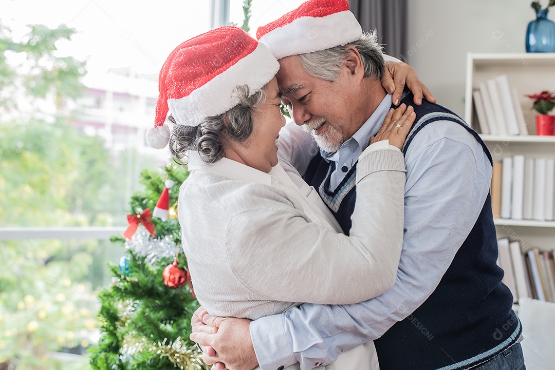 Casal de idosos senta-se no sofá da sala e canta juntos no dia de natal.