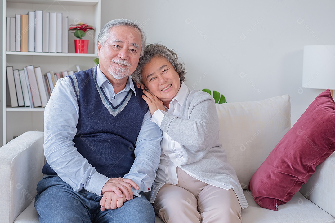 Marido e esposa sênior sentam-se alegremente no sofá em sua casa