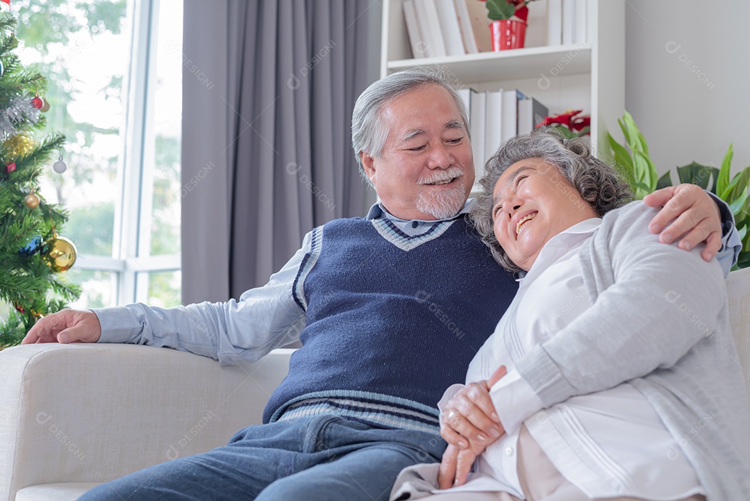 Casal idosos sentou-se e olhou para tablet na sala de estar com uma árvore de natal