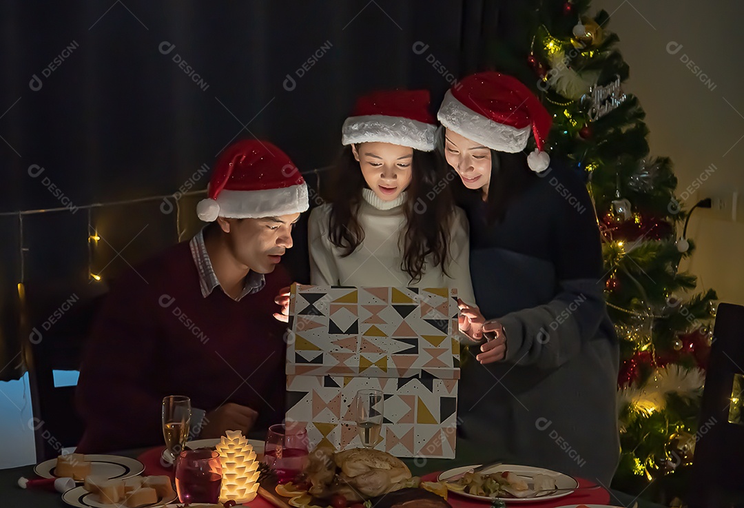Surpresa, pais e filhas abrem uma caixa de presente no dia de Natal