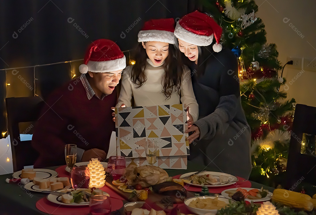 Surpresa, pais e filhas abrem uma caixa de presente no dia de Natal