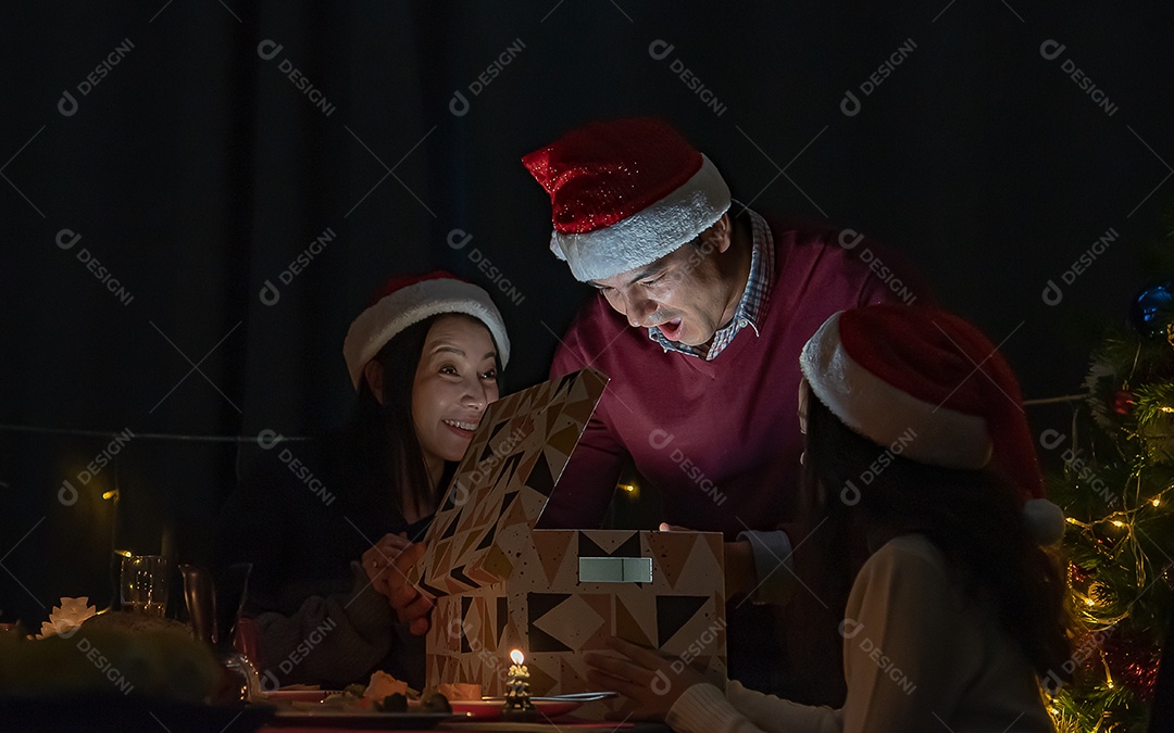 Surpresa, pais e filhas abrem uma caixa de presente no dia de Natal