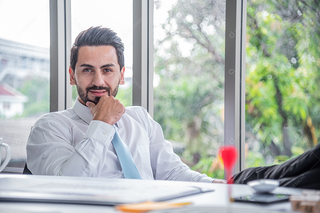 Homem de negócios sentado com confiança no escritório moderno e olhando