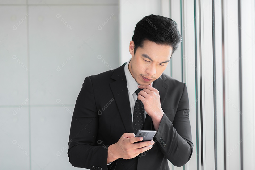 Homem de negócios que está contemplando ao usar o telefone celular