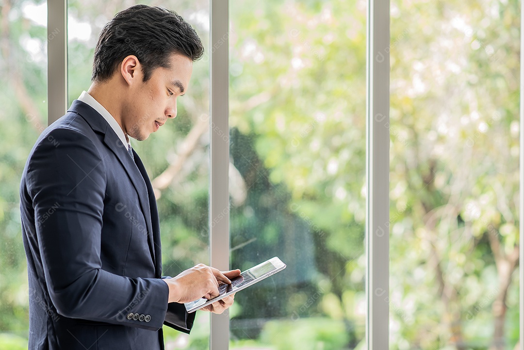 Empresário em pé contemplando enquanto usa tablet