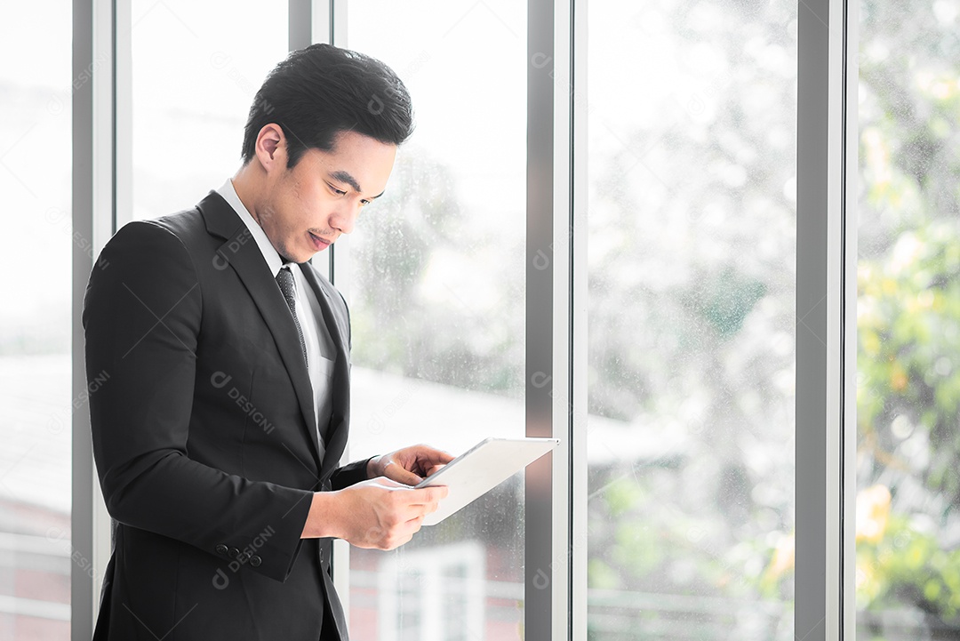 Empresário em pé contemplando enquanto usa tablet