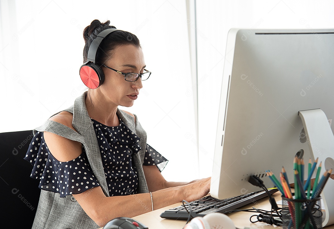 Mulher idosa usando um fone de ouvido sem fio está estudando computador