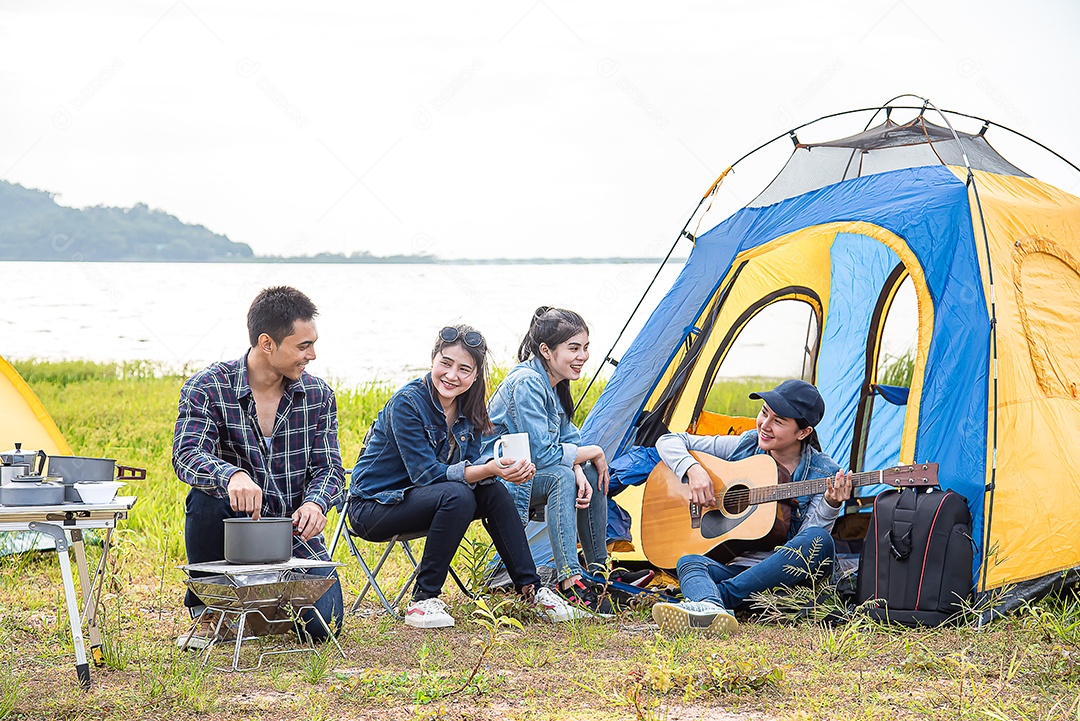 Grupo de amigos viajantes relaxa, monta a barraca e prepara o jantar